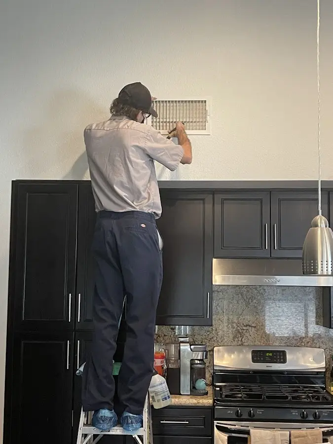 Technician inspecting an air vent during HVAC service in Black Forest